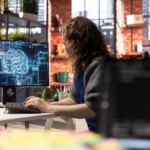 modern ofis ortamında bilgisayar başında çalışan bir kişinin ekranda yapay zekâ ve beyin ağı görselleştirmesiyle analiz yapması, yapay zekâ araçlarıyla verimli ve odaklı çalışma konsepti